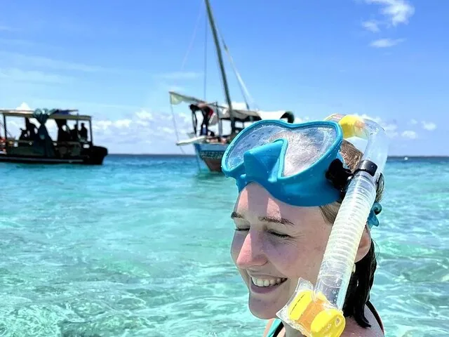 Woman with snorkel mask resting on head in clear shallow water