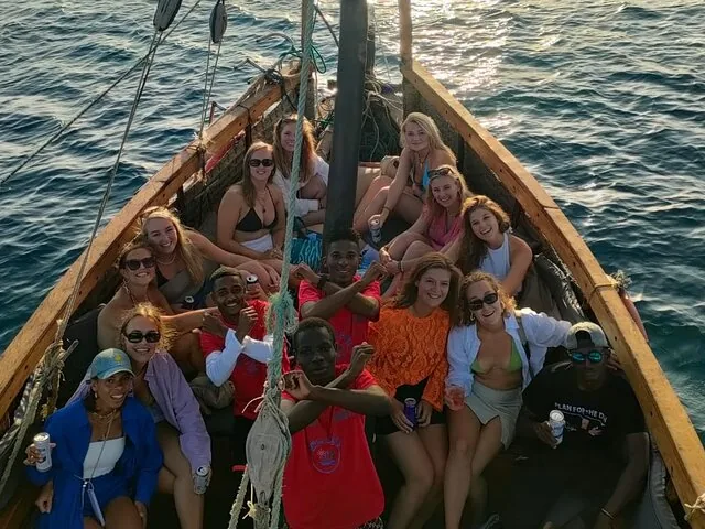 Group of happy tourists posing on a wooden boat at sunset
