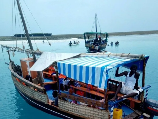 Dhow boat in clear turquoise water near Wasini Island with other boats